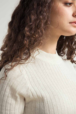 Closeup of woman wearing white recycled ribbed short sleeve Renza sweater by Rifo. 