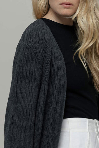 Close-up of woman wearing dark grey knit cardigan and black t-shirt. 