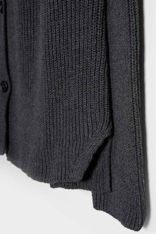 Close-up of sleeve and waist of dark grey knit sweater. 