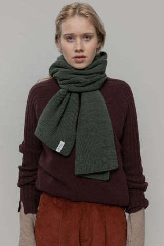Woman in front of grey background wearing brown knit sweater and forest green knit Federico Scarf by Rifo. 