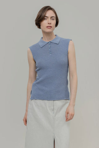Woman wearing a blue sleeveless ribbed knit top with a collar against a plain background