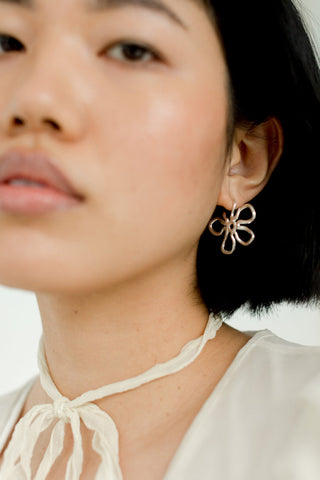 Woman wearing sterling silver Flora Medium hoop earrings by Kara Yoo. 