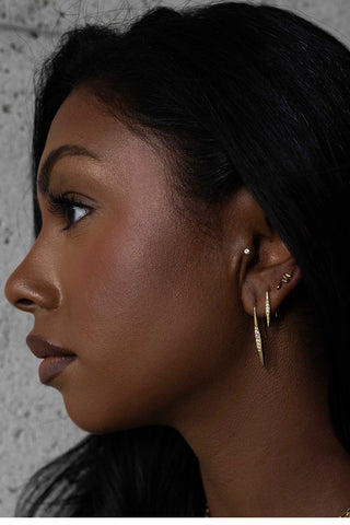 Woman wearing gold shift earrings. 