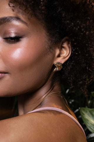 Close-up of a woman wearing gold earrings with a blurred background