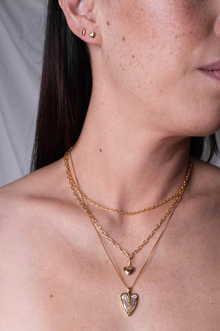 Woman wearing three necklaces, including the Sarah Mulder Little Puffed Heart Necklace. 