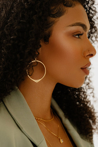 Woman wearing gold plated Staff Party hoop earrings by Sarah Mulder. 