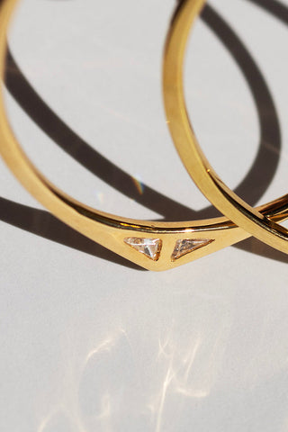 Close-up of gold plated Staff Party hoop earrings by Sarah Mulder. 