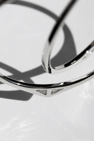Close-up of rhodium plated Staff Party hoop earrings by Sarah Mulder. 