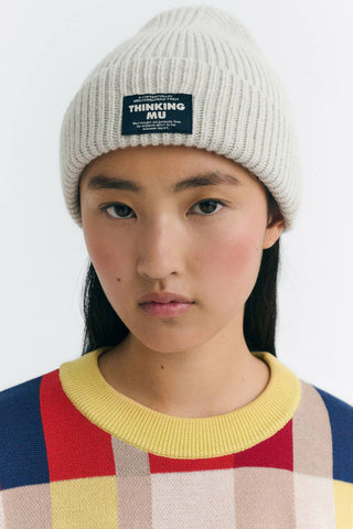 Woman with multicoloured sweater and ecru rib knit wool Amor Beanie by Thinking Mu.