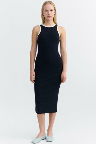 Woman wearing navy sleeveless midi length dress with white trim around neck and arms. 