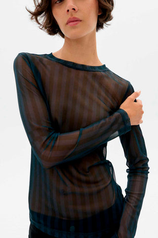 Model in front of white background wearing sheer blue stripe Esqué Tere top by Thinking Mu. 