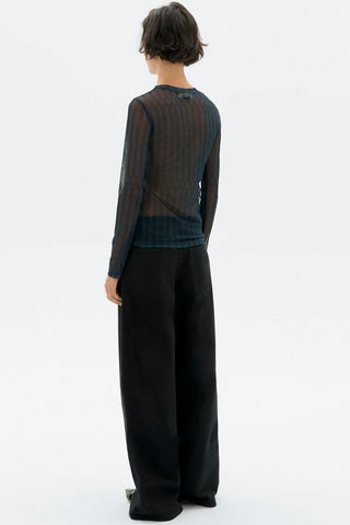 Back view of model in front of white background wearing sheer blue stripe Esqué Tere top by Thinking Mu. 
