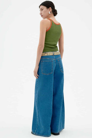 Back view of woman wearing jeans and green tank top with orange trim. 