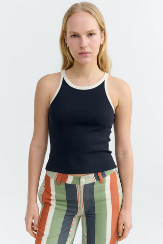 Woman wearing navy tank top with cream trim and multi-colour striped pants. 