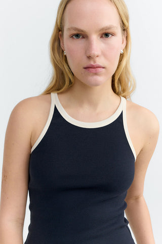 Close-up of woman wearing navy tank top with cream trim. 