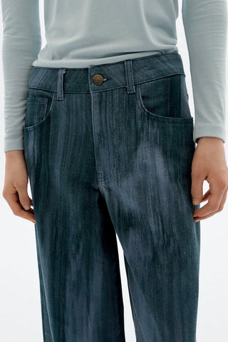 Close-up of woman in front of white background wearing light blue long sleeve top and wide leg Heda jeans by Thinking Mu. 