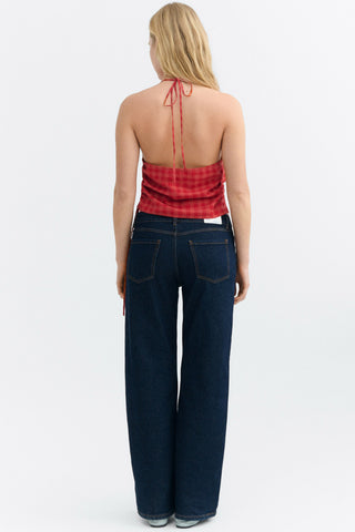 Back view of woman wearing red checkered halter neck top with dark denim jeans. 