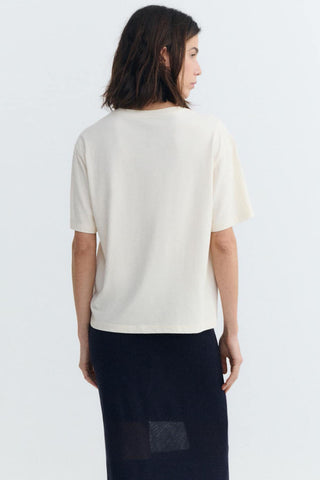 Back view of woman wearing white t-shirt and navy blue skirt. 