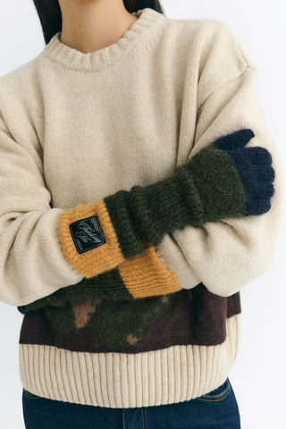 Close-up of model wearing cream sweater and green, navy & yellow Maggie gloves by Thinking Mu. 