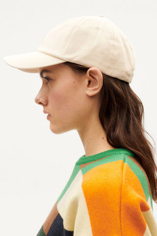 Model wearing sun embroidered ivory Chris cap by Thinking Mu. 