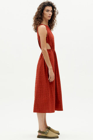Side view of woman wearing organic red orange Kin dress by Thinking Mu. 