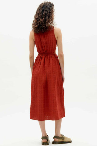Back view of woman wearing organic red orange Kin dress by Thinking Mu. 