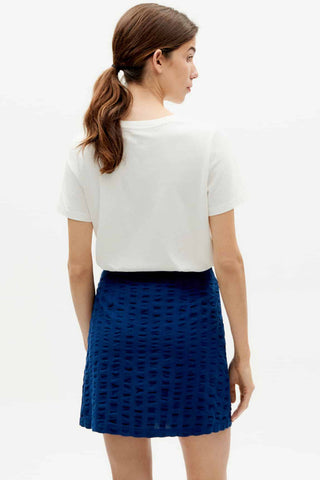 Woman wearing white t-shirt and navy blue organic cotton Milena short wrap skirt by Thinking Mu. 