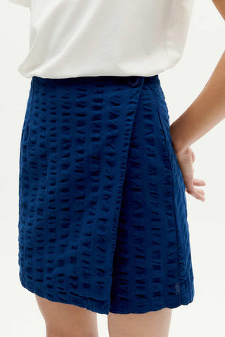 Close-up of woman wearing white t-shirt and navy blue organic cotton Milena short wrap skirt by Thinking Mu. 