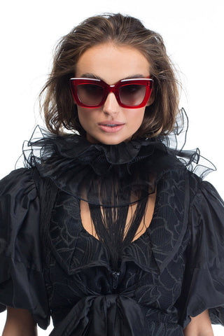 Model wearing Valley Eyewear Brigada sunglasses with transparent red frames and black gradient lenses