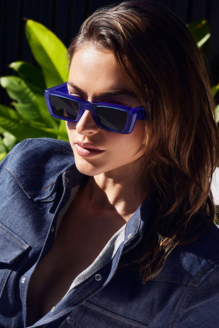 Woman wearing Valley Eyewear Lahara Sunglasses in electric blue with black gradient lenses. 