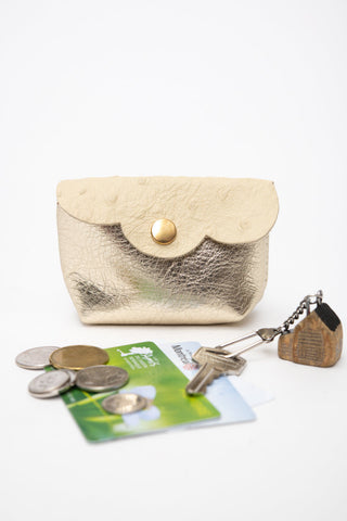 Beige with metallic gold leather coin pouch shown with coins, metro card & keys. 