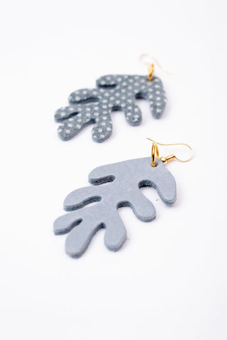 Coral shaped leather earrings on white background, one shows front with blue and white dot design, second shows back with solid blue suede. 
