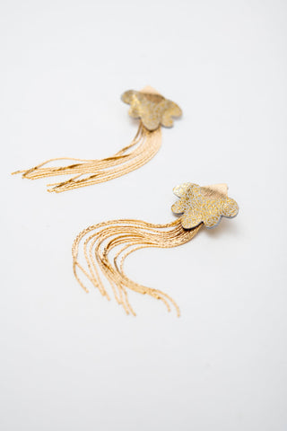 A pair of gold-toned earrings with textured flower-like tops and long dangling fringe, photographed on a plain white background.