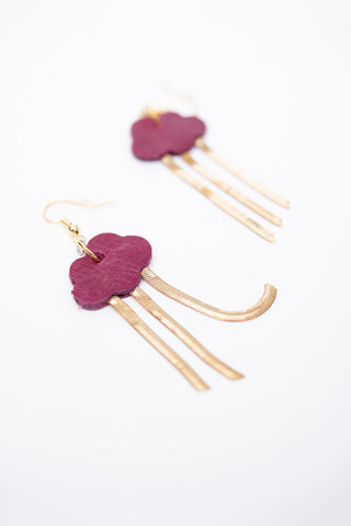 A pair of cloud-shaped drop earrings with raspberry pink leather cloud with three dangling gold-tone chains, shown on a clean white background.