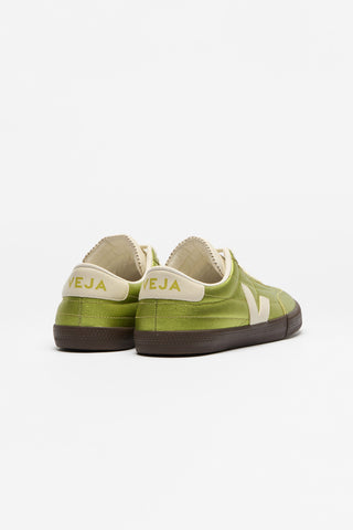 A pair of low-top sneakers shown from the back, featuring metallic green leather uppers with cream-colored Veja V logo and heel tabs, dark brown soles. 