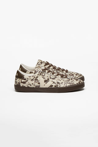 A pair of biege low-top sneakers with brown cowhide print, brown laces and cream Veja V logo, photographed from the side on a clean white background.