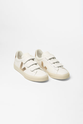 Pair of white Veja sneakers with light  gold V logo. 
