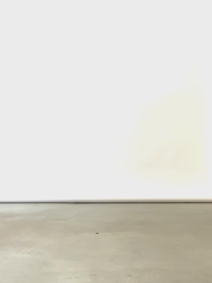A woman wearing a white button up shirt with 3/4 length sleeves tucked into black pants, walking across frame in minimal studio. 