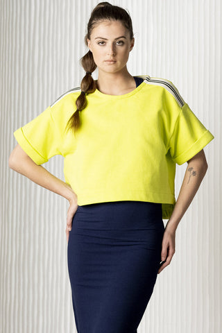 Model wearing neon yellow BodyBag Industry crop top with racing stripe along shoulders. 
