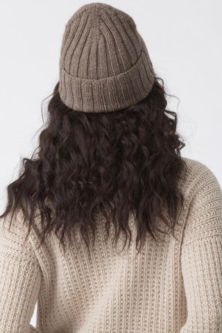 Back view of model wearing oat brown thick knit yak wool hat by Dinadi. 
