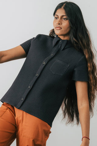 Model wearing Jennifer Glasgow Asherah Button Up in black organic cotton waffle weave. 