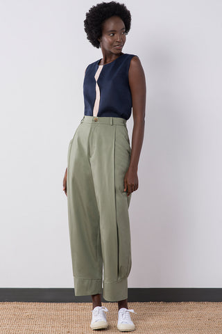 Model wearing sage organic cotton pleated Jennifer Glasgow Ceres pants with cuffed ankle.