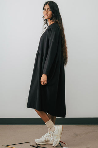 Side view of model wearing Jennifer Glasgow Mazu dress in black organic cotton. 