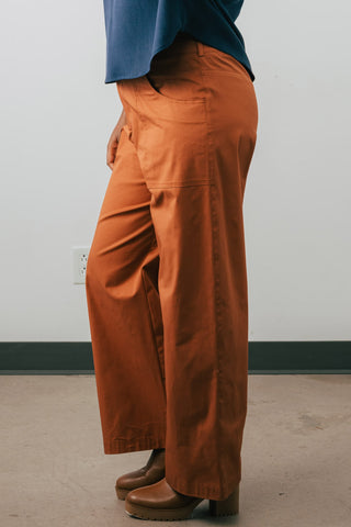 Side view of model wearing organic cotton Jennifer Glasgow Moray pants in rust. 