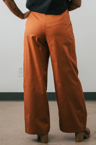 Back view of model wearing organic cotton Jennifer Glasgow Moray pants in rust. 