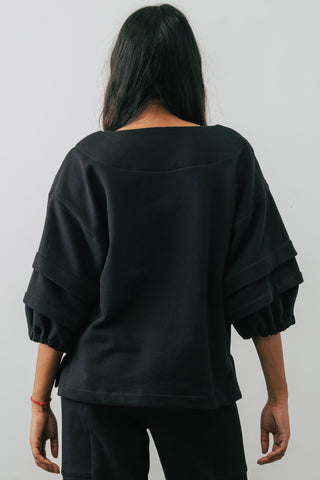 Back view of model wearing black organic cotton Pearl Sweater with pleated sleeves by Jennifer Glasgow.
