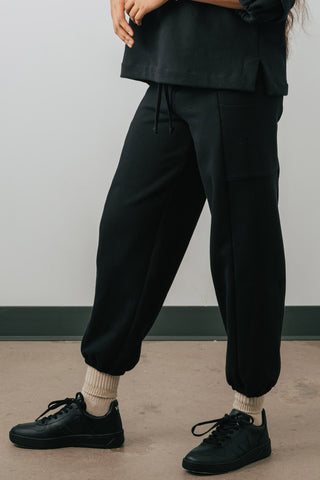 Side view of model wearing black colour organic cotton Jennifer Glasgow Ridley Sweatpants. 