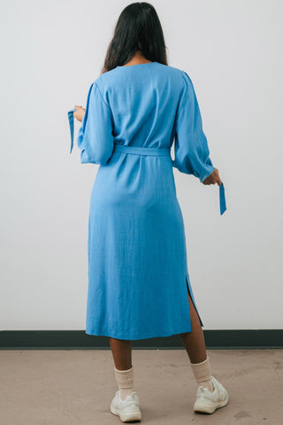 Back view of model is wearing blue midi length button up Umiko shirt dress by Jennifer Glasgow. 