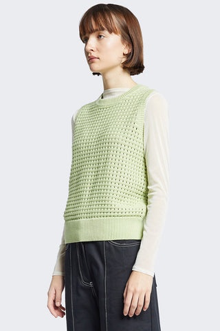 Side view of model wearing green sleeveless crochet Arch Vest by Kloke. 