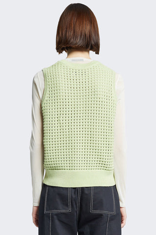 Back view of model wearing green sleeveless crochet Arch Vest by Kloke. 